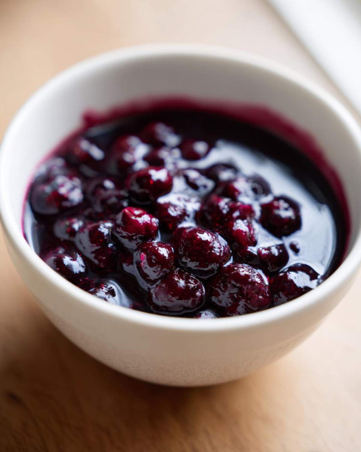 Close-up of whole blueberries simmering in rich, dark liquid, part of the Homemade Blueberry Syrup recipe.