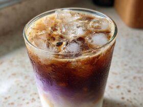 Close-up of a refreshing Iced Lavender Latte showing distinct layers of milk, purple syrup, and dark espresso over ice.