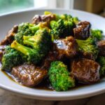 A close-up, appetizing shot of tender beef chunks coated in savory sauce mixed with bright green broccoli florets, showcasing the Instant Pot Beef and Broccoli.