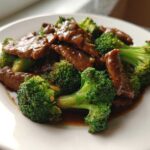 A close-up serving of glossy Instant Pot Beef and Broccoli featuring tender beef strips and bright green florets coated in savory sauce.