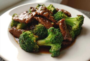 A close-up serving of glossy Instant Pot Beef and Broccoli featuring tender beef strips and bright green florets coated in savory sauce.