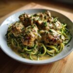 Close-up of Keto Chicken Alfredo featuring seared chicken pieces over zucchini noodles in a creamy sauce.