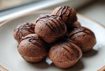 A stack of rich, dark brown Keto Chocolate Peanut Butter Fat Bombs drizzled with melted chocolate.