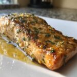Close-up of a perfectly cooked Keto Garlic Butter Salmon fillet glistening with butter sauce and fresh herbs.