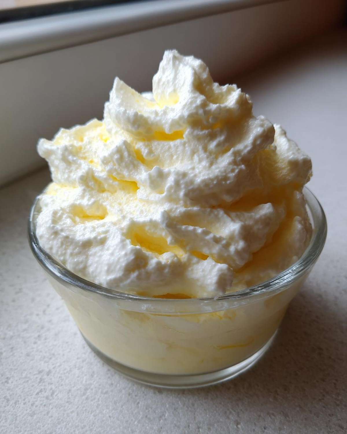 Close-up of Keto Lemon Cheesecake Mousse topped with piped whipped cream in a small glass dish.