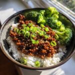 A close-up of a Korean Ground Beef Bulgogi Bowl served over white rice with steamed broccoli and garnished with green onions and sesame seeds.