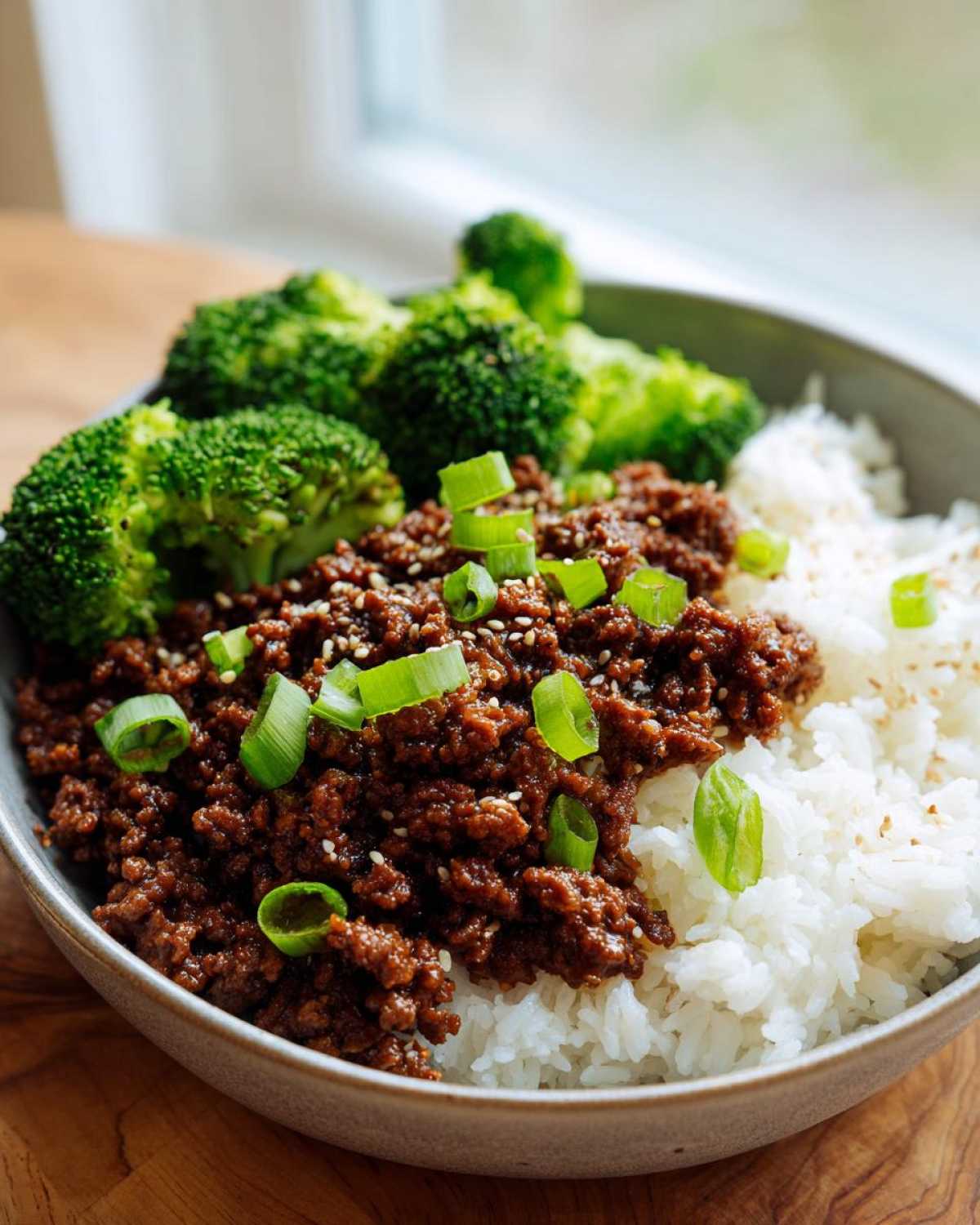 Close-up of a Korean Ground Beef Bulgogi Bowl featuring savory ground beef, white rice, steamed broccoli, and green onion garnish.