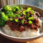 A close-up of Korean Ground Beef Bulgogi Bowls featuring saucy ground beef over white rice, topped with green onions and sesame seeds, served with steamed broccoli.