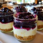 Three individual Lemon Blueberry Cheesecake Jars layered with graham cracker crust, creamy filling, and blueberry topping.