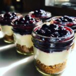 Close-up of several Lemon Blueberry Cheesecake Jars layered with graham cracker crust, cream cheese filling, and blueberry topping.