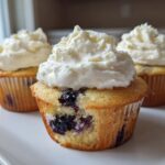Three Lemon Blueberry Cupcakes with thick swirls of cream cheese frosting on a white plate.