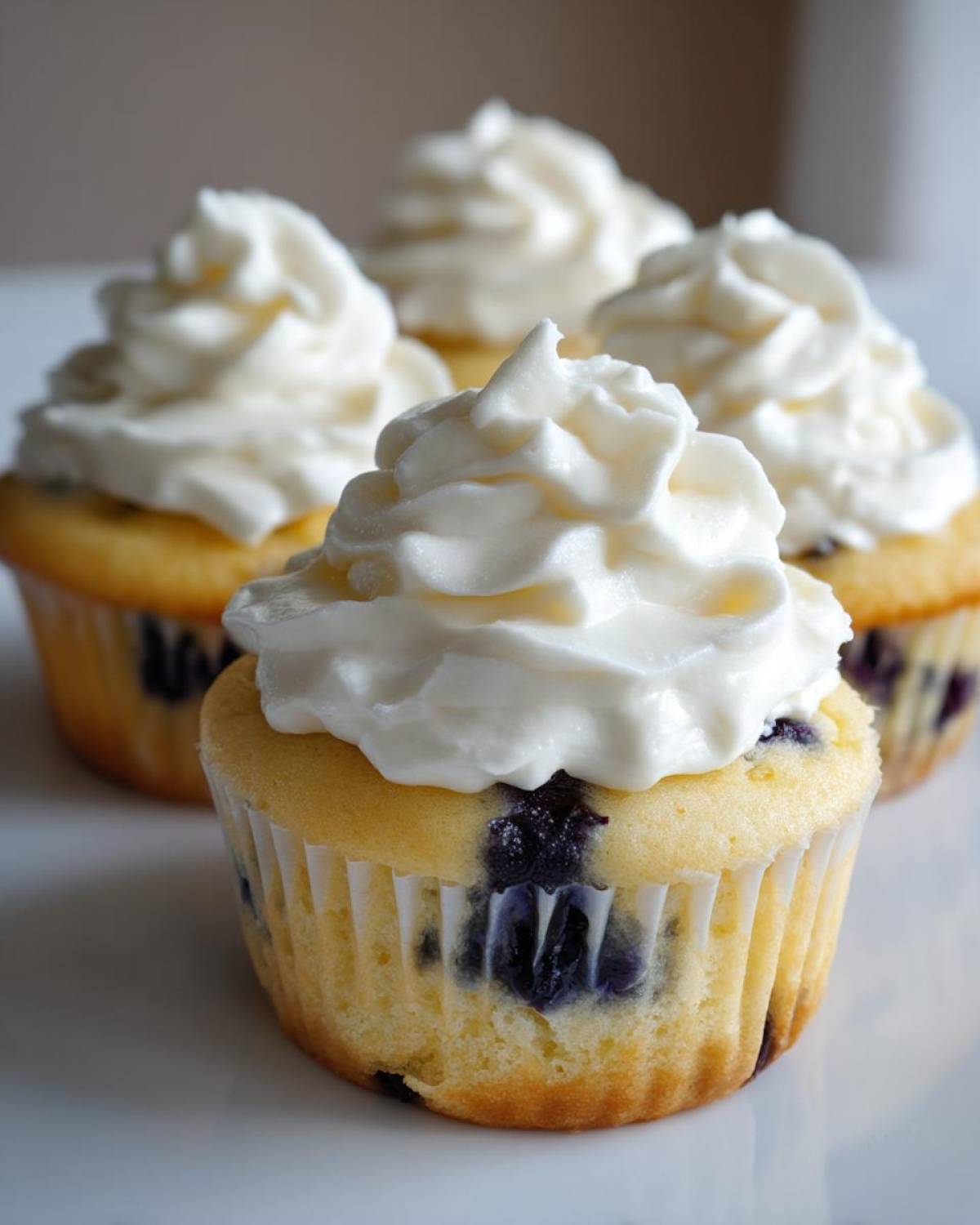 Close-up of Lemon Blueberry Cupcakes topped with swirls of white cream cheese frosting.