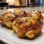 Close-up of four perfectly roasted Lemon Garlic Roasted Chicken Thighs with crispy, seasoned skin.