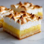 A square serving of Lemon Meringue Pie Bars showing a shortbread crust, bright yellow lemon filling, and peaks of toasted meringue.