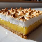 Close-up of a single square Lemon Meringue Pie Bars showing graham cracker crust, bright yellow lemon filling, and toasted meringue peaks.