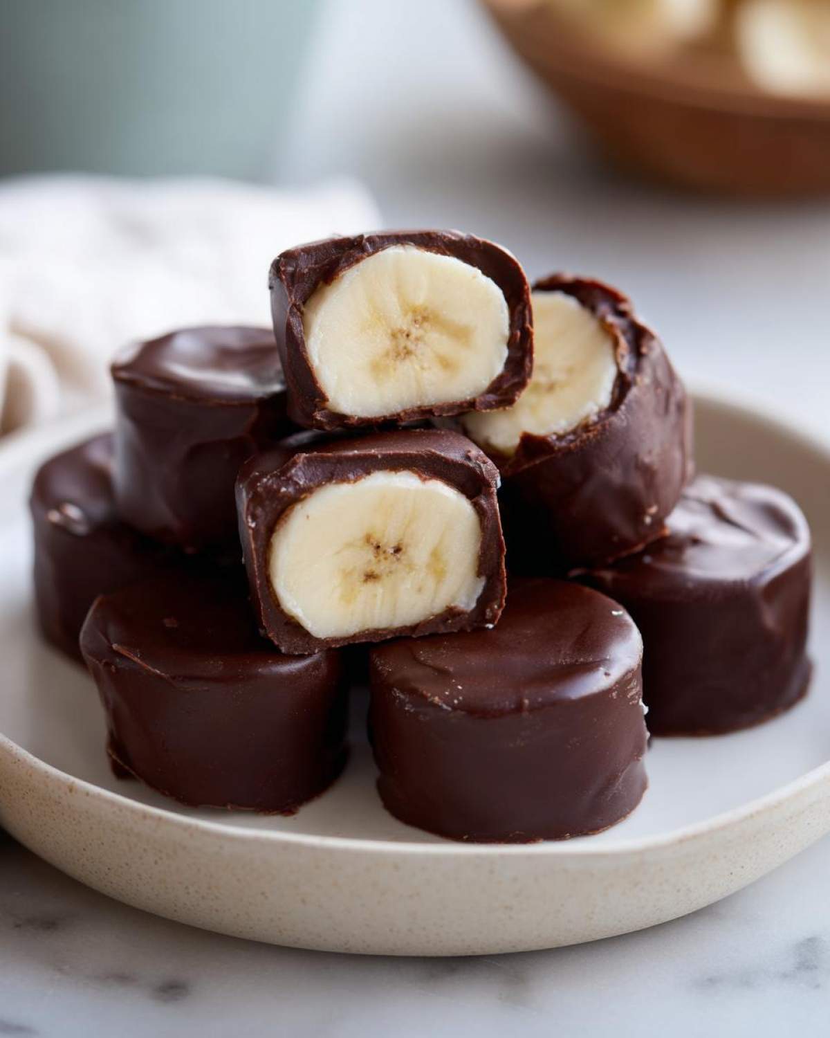 A stack of No-Bake Chocolate Covered Banana Bites, showing the creamy banana center inside the dark chocolate shell.