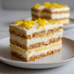 Close-up of a layered slice of No-Bake Lemon Icebox Cake topped with bright yellow lemon zest.