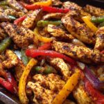 Close-up of seasoned chicken strips mixed with colorful bell peppers and onions in a pan, ready for One-Pan Chicken Fajitas with Peppers and Onions.