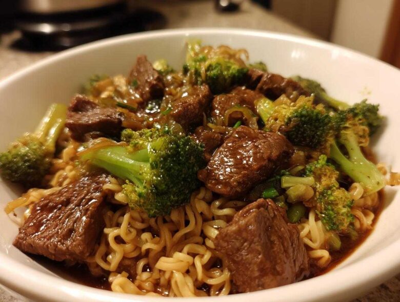 Close-up of a white bowl filled with One-Pot Beef and Broccoli Ramen Noodles, featuring savory beef chunks and bright green broccoli florets.