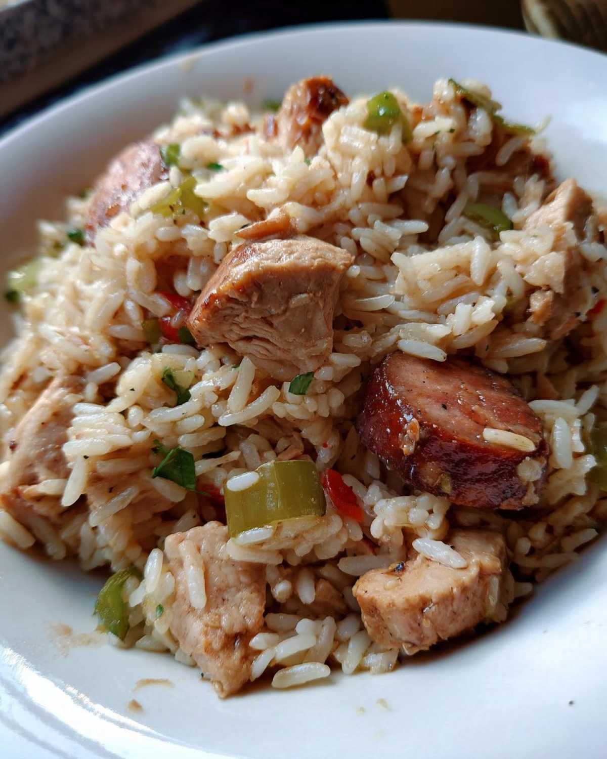 A close-up view of a serving of One-Pot Chicken Jambalaya featuring rice, chunks of chicken, and slices of sausage.
