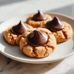 Close-up of four classic Peanut Butter Blossom Cookies with a chocolate kiss pressed into the center.
