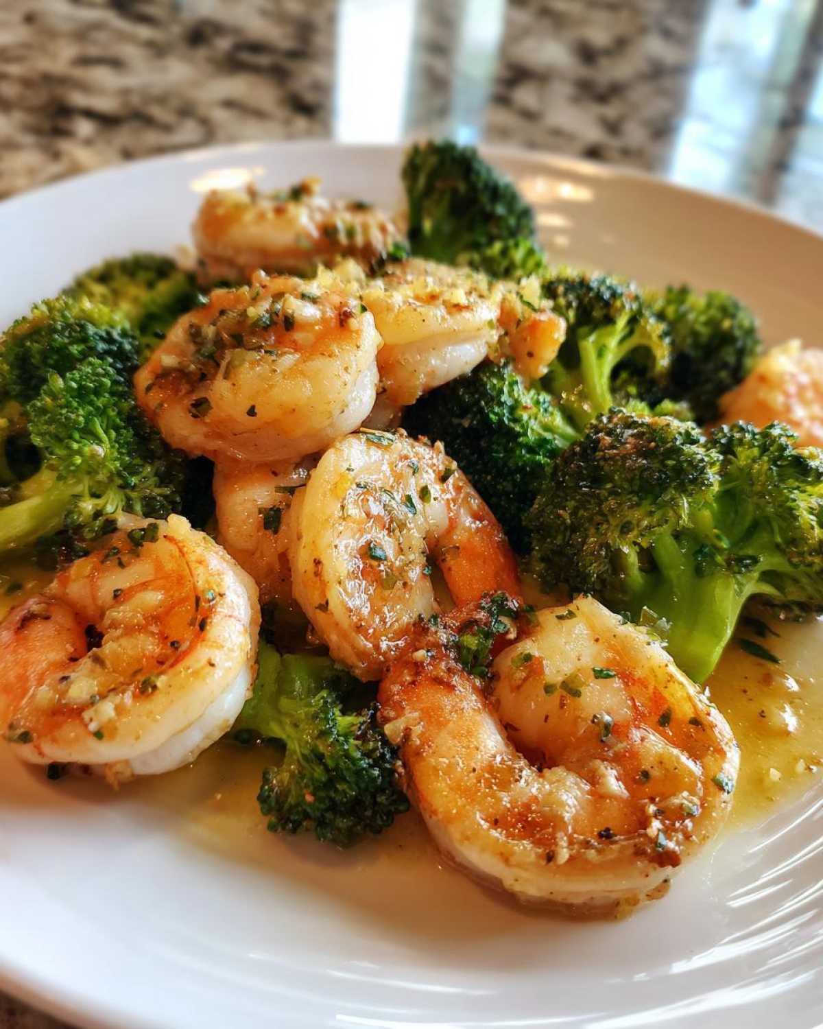 Close-up of cooked shrimp coated in garlic butter sauce served with bright green broccoli florets, part of the Sheet Pan Garlic Butter Shrimp and Broccoli.