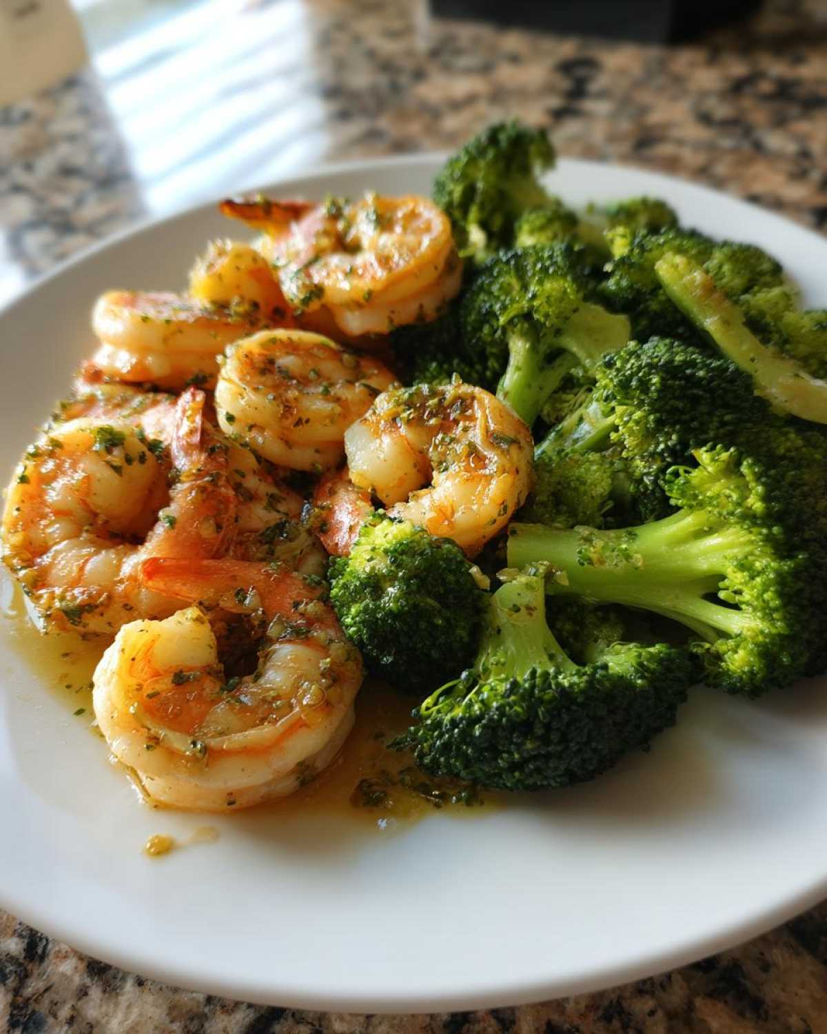 Close-up of juicy Sheet Pan Garlic Butter Shrimp and Broccoli served on a white plate.