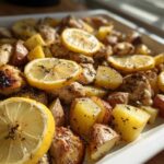 Close-up of Sheet Pan Lemon Pepper Chicken and Potatoes with roasted lemon slices.