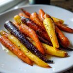 Close-up of vibrant Sheet Pan Roasted Rainbow Carrots with Honey, glistening on a white plate.