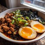 A close-up bowl of Spicy Miso Ramen featuring rich broth, ground meat, scallions, nori, and two perfectly halved soft-boiled eggs.