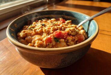 A steaming bowl of Spicy Turkey White Bean Chili featuring ground turkey, white beans, and tomatoes, set near a sunny window.