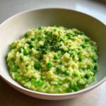 A close-up of creamy Spring Pea and Mint Risotto, vibrant green with whole peas and topped with fresh parsley.