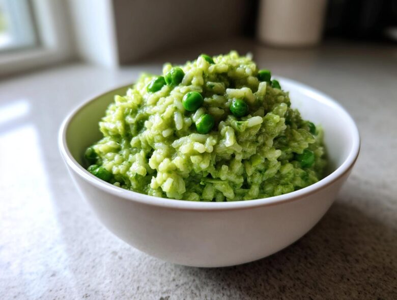 A close-up of creamy Spring Pea and Mint Risotto, topped with whole peas, served in a white bowl.