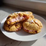 Close-up of Strawberry Cheesecake Stuffed Cookies, one broken open showing pink filling.