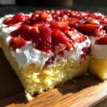 Close-up of a slice of Strawberry Shortcake Sheet Cake showing moist yellow cake, thick whipped cream, and glazed strawberries.