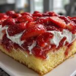 Close-up of a thick slice of Strawberry Shortcake Sheet Cake featuring yellow sponge, whipped cream, and glossy sliced strawberries.