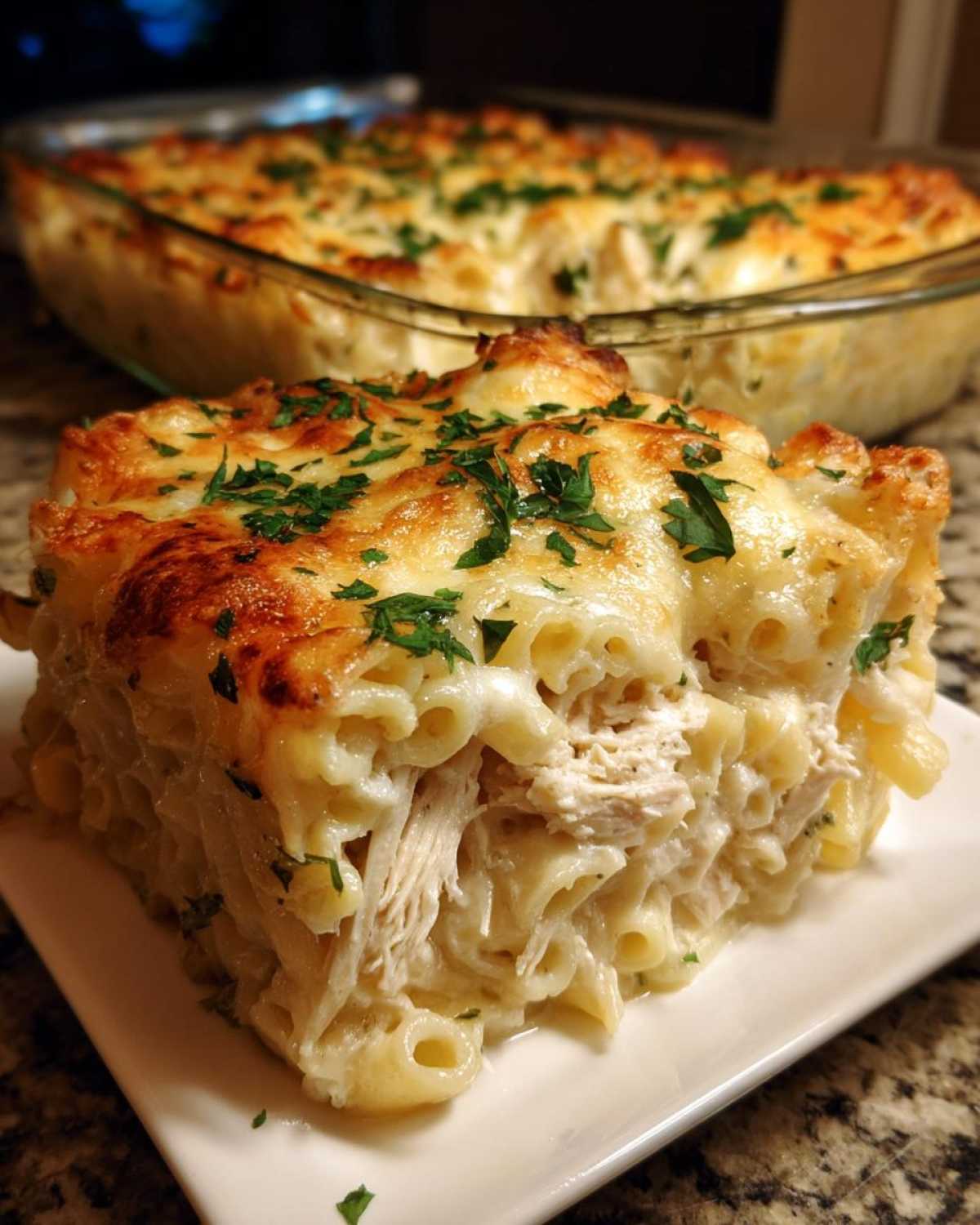 A thick slice of Cheesy Chicken Alfredo Bake with Mozzarella, featuring pasta, shredded chicken, and a golden, bubbly cheese topping.