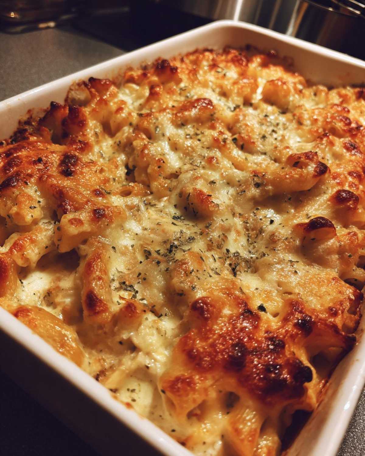 Close-up of baked Cheesy Chicken Pasta with Creamy Sauce, featuring a bubbly, golden-brown cheese crust.