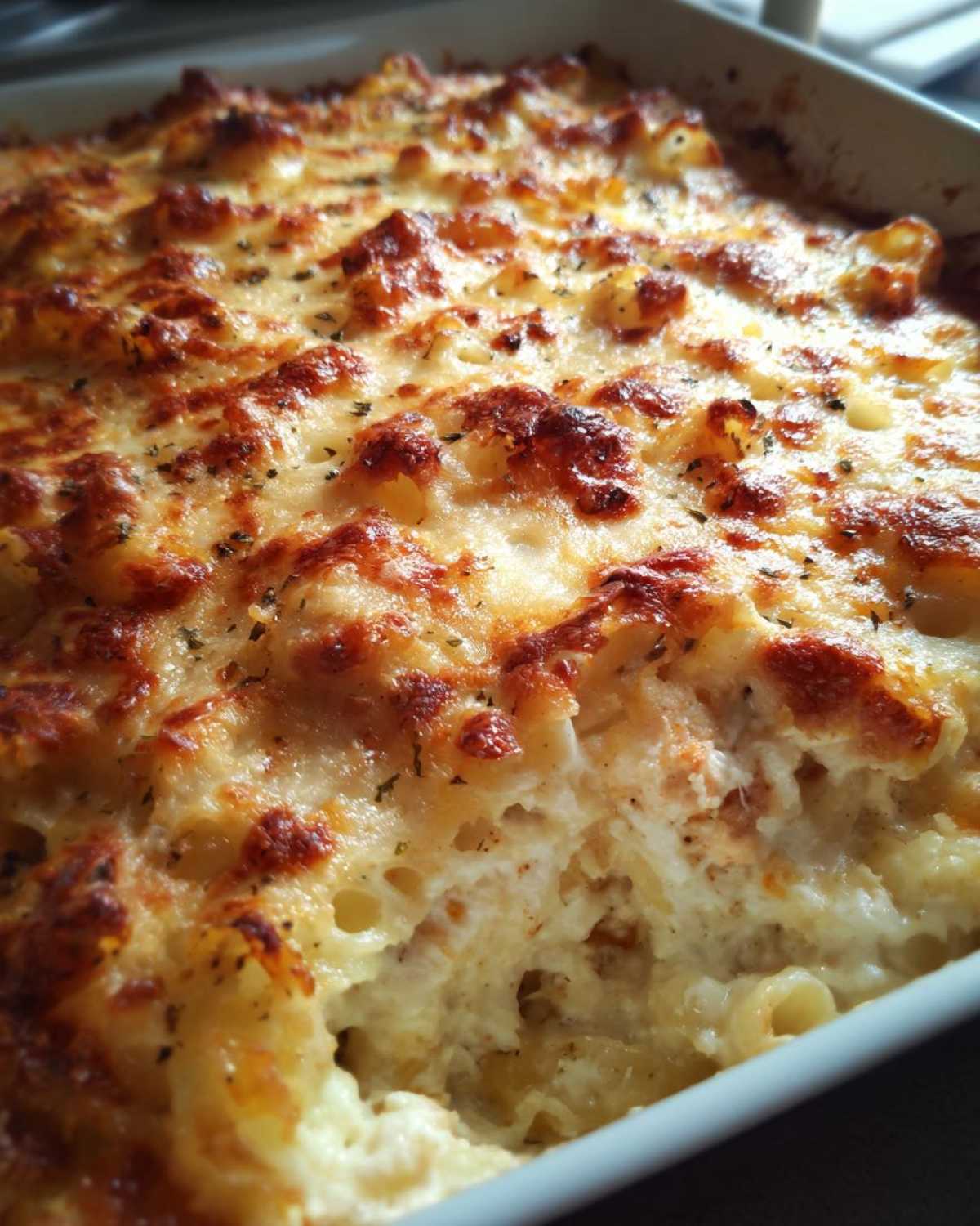 Close-up of baked Cheesy Chicken Pasta with Creamy Sauce, featuring a bubbly, golden-brown cheese crust.