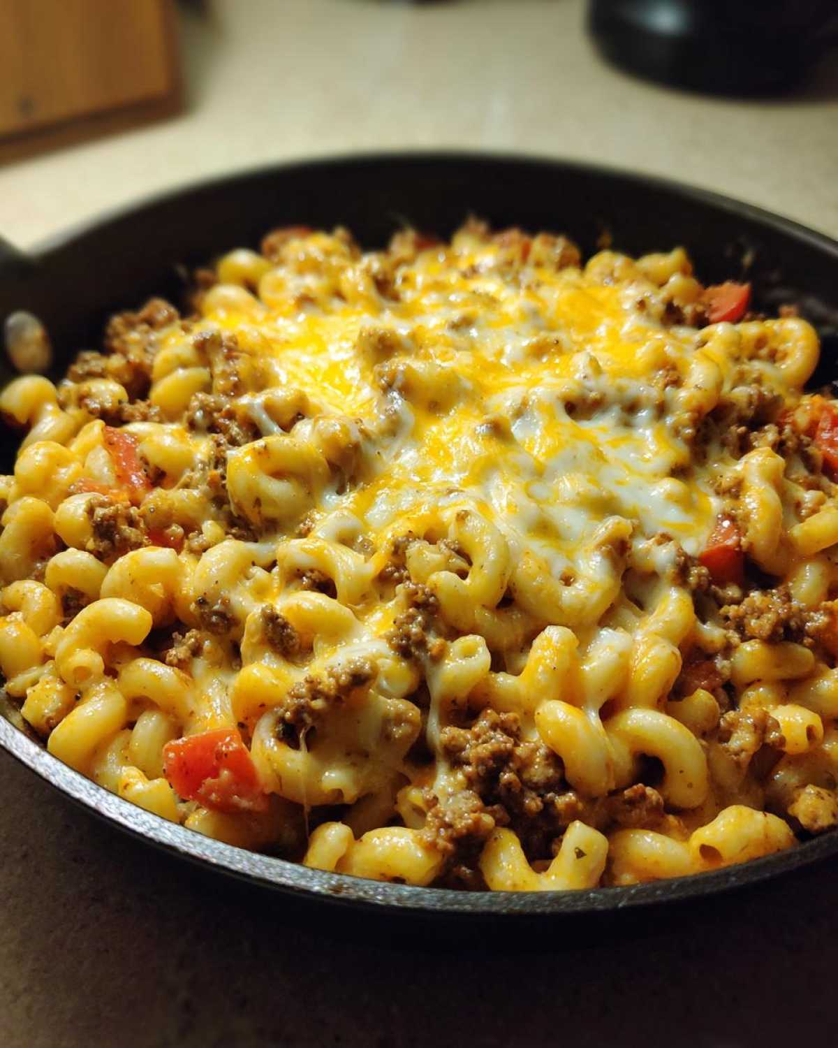 Close-up of Cheesy Ground Beef Pasta Skillet Comfort Food topped with melted cheddar and Monterey Jack cheese.