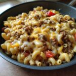 Close-up of Cheesy Ground Beef Pasta Skillet with melted cheddar and mozzarella over elbow macaroni and ground beef.