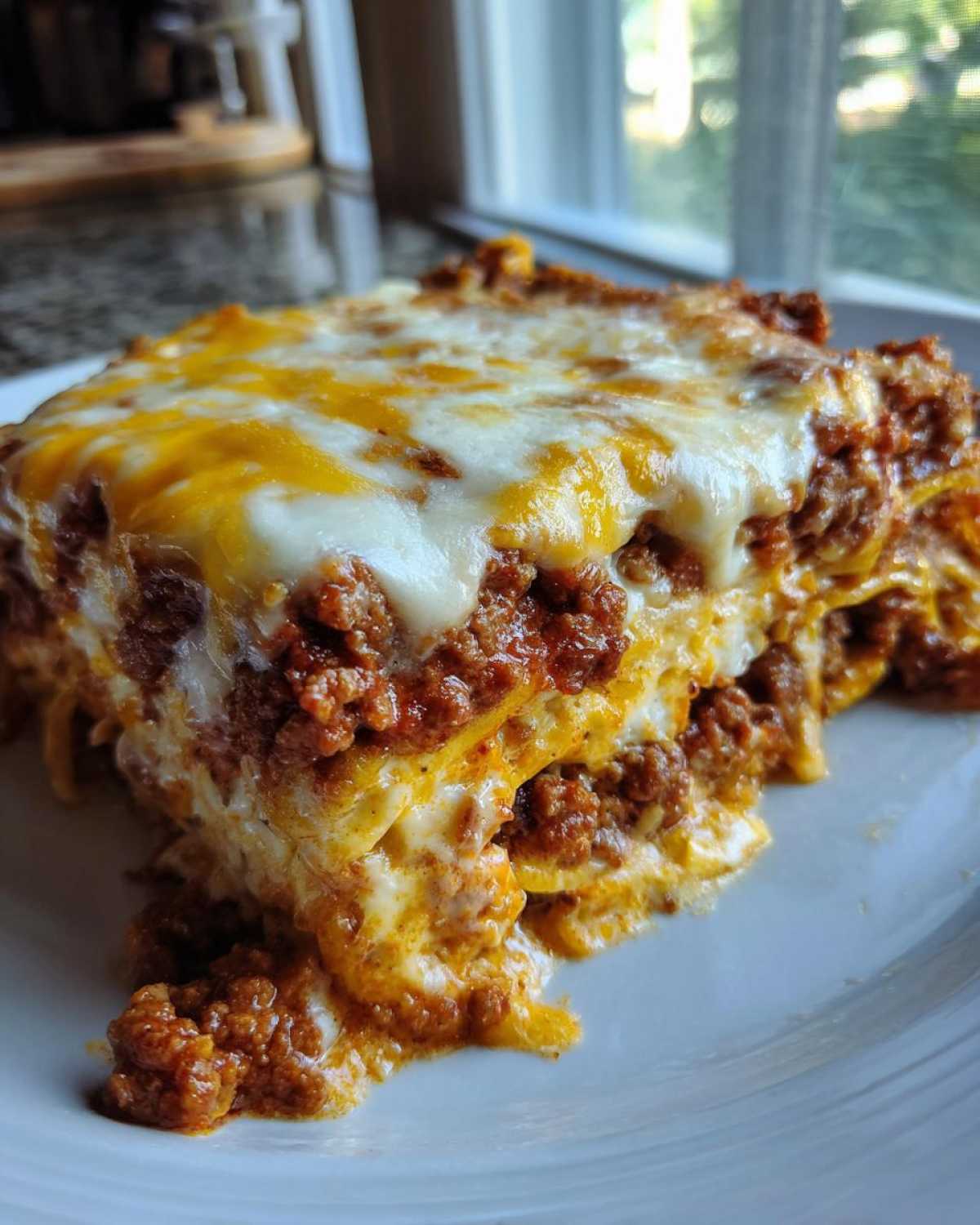 Close-up of a hearty slice of Cheesy Ground Beef Queso Bake Comfort Dish, layered and topped with melted cheese.