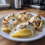 A plate of Cheesy Ground Beef Stuffed Shells with Cream Sauce, generously topped with melted cheese and savory meat filling.