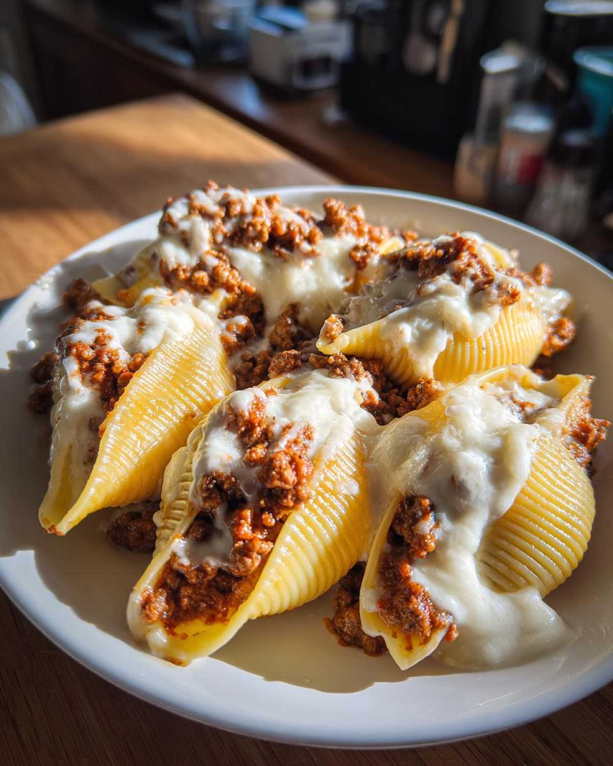 A close-up of jumbo pasta shells filled with ground beef and topped with melted cheese in a creamy sauce, perfect Cheesy Ground Beef Stuffed Shells.