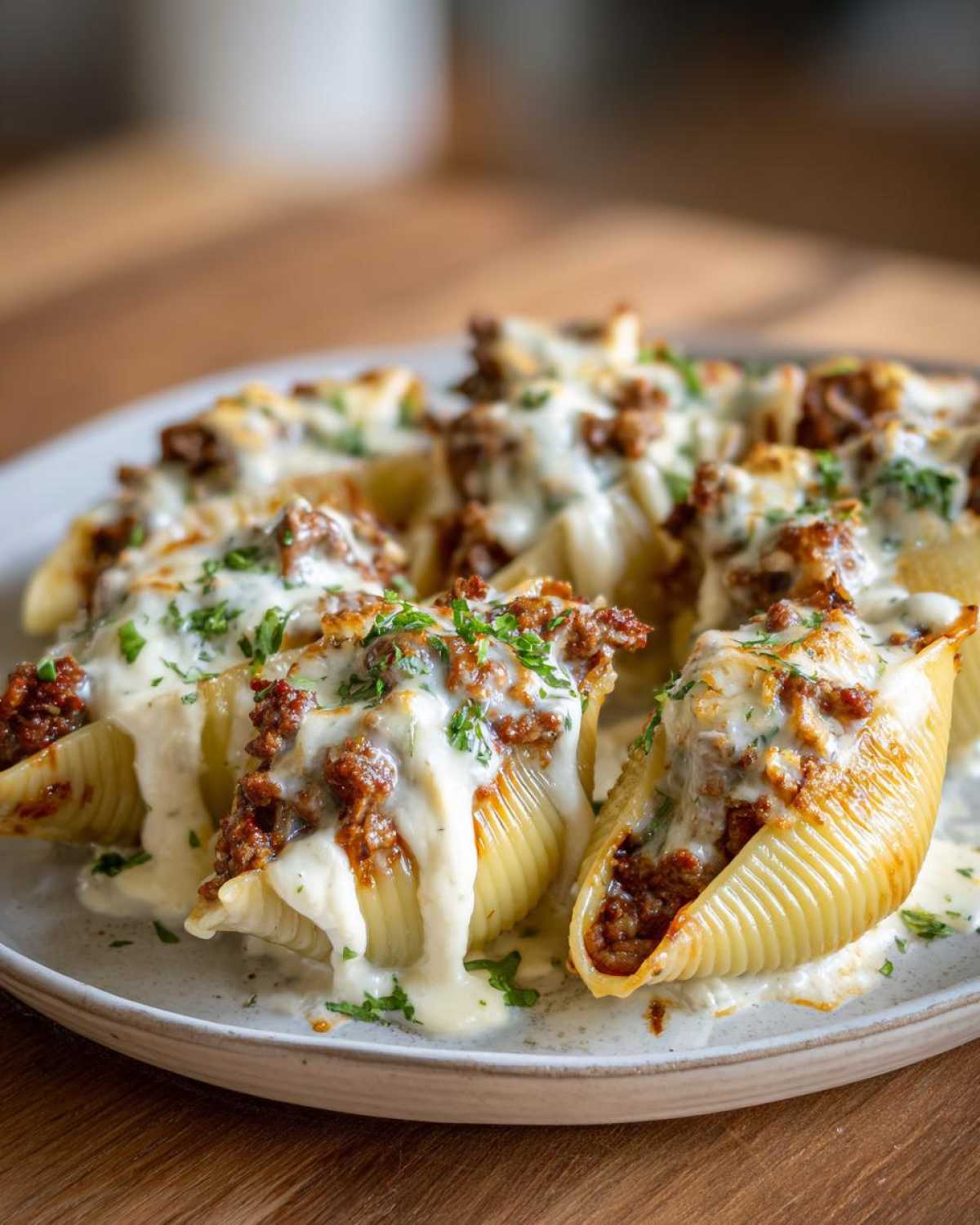 Close-up of Cheesy Ground Beef Stuffed Shells with Cream Sauce, topped with melted cheese and parsley.