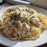 A serving of Creamy Alfredo Chicken Pasta Easy Recipe featuring fettuccine, chunks of chicken, and garnished with parsley.