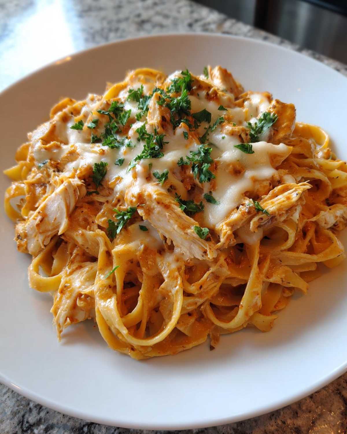 Close-up of Creamy Cajun Chicken Alfredo Bake featuring fettuccine pasta, shredded chicken, melted cheese, and parsley garnish.