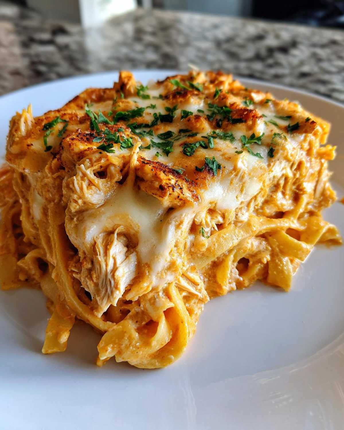 A close-up serving of Creamy Cajun Chicken Alfredo Bake with melted cheese and parsley.
