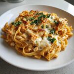 A close-up of a serving of Creamy Cajun Chicken Alfredo Bake with melted cheese and parsley.