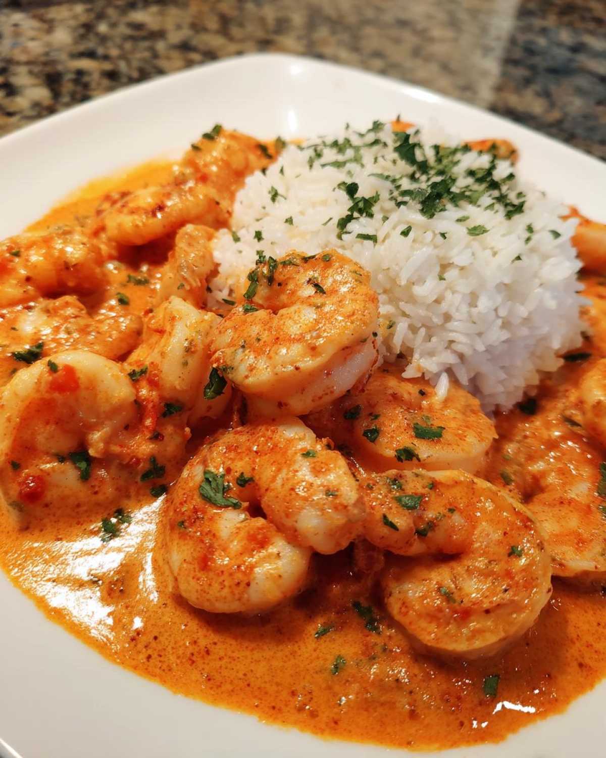 Close-up of Creamy Cajun Shrimp and Rice Skillet featuring shrimp in rich orange sauce next to white rice.